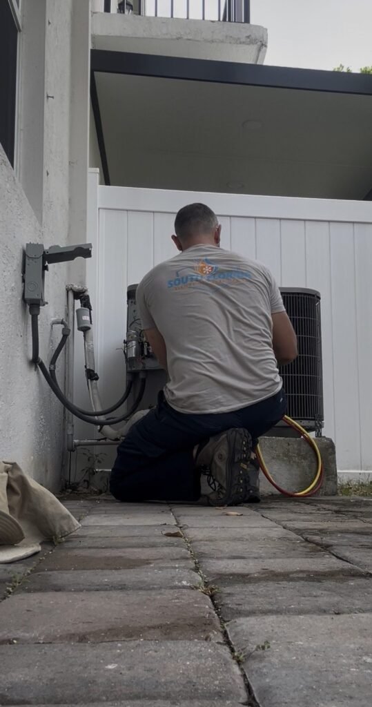 South Florida Heating and Air Conditioning technician servicing a condenser unit outside a home
